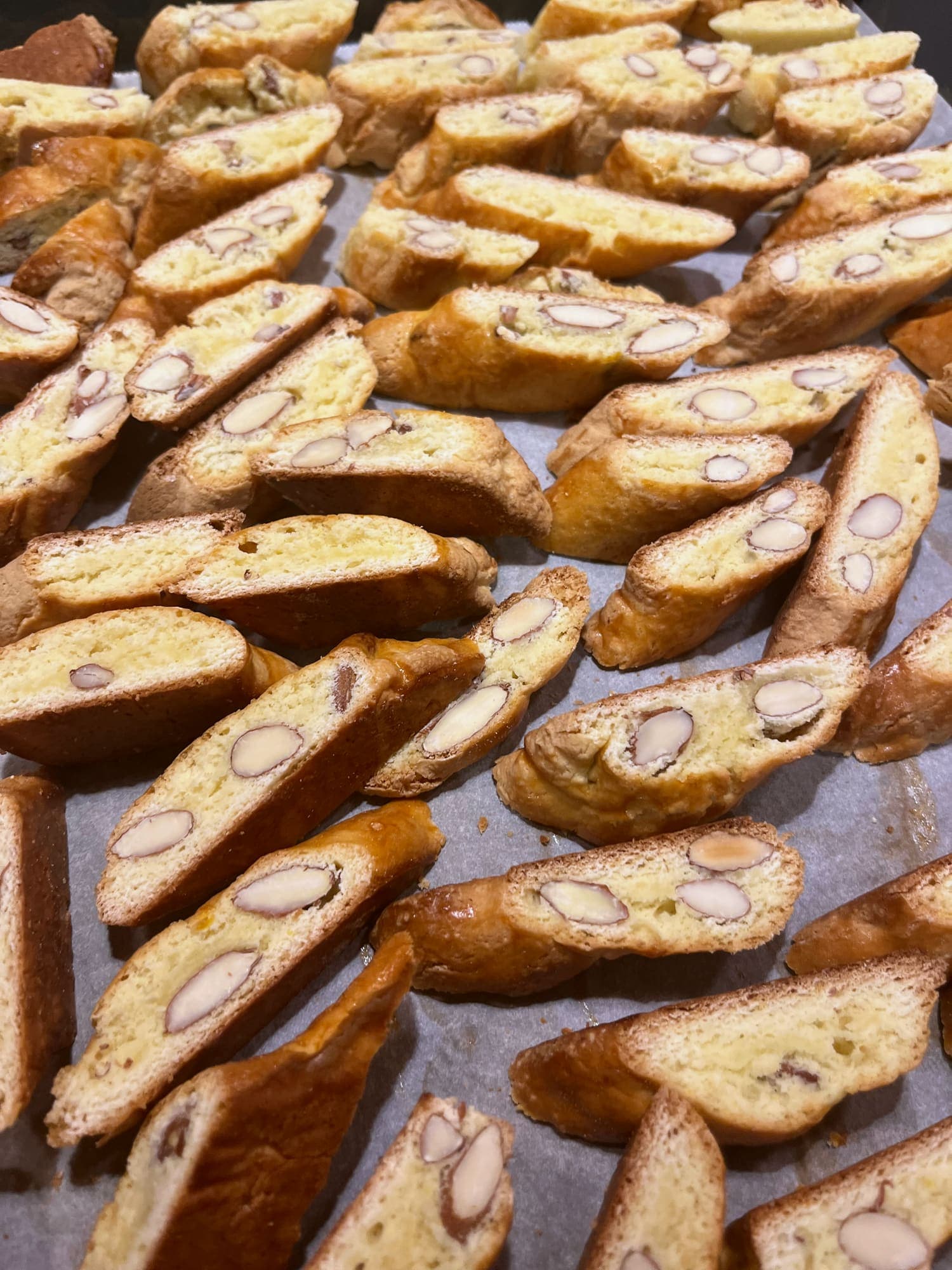 Slices of almond cantucci cooling on a lined baking tray.