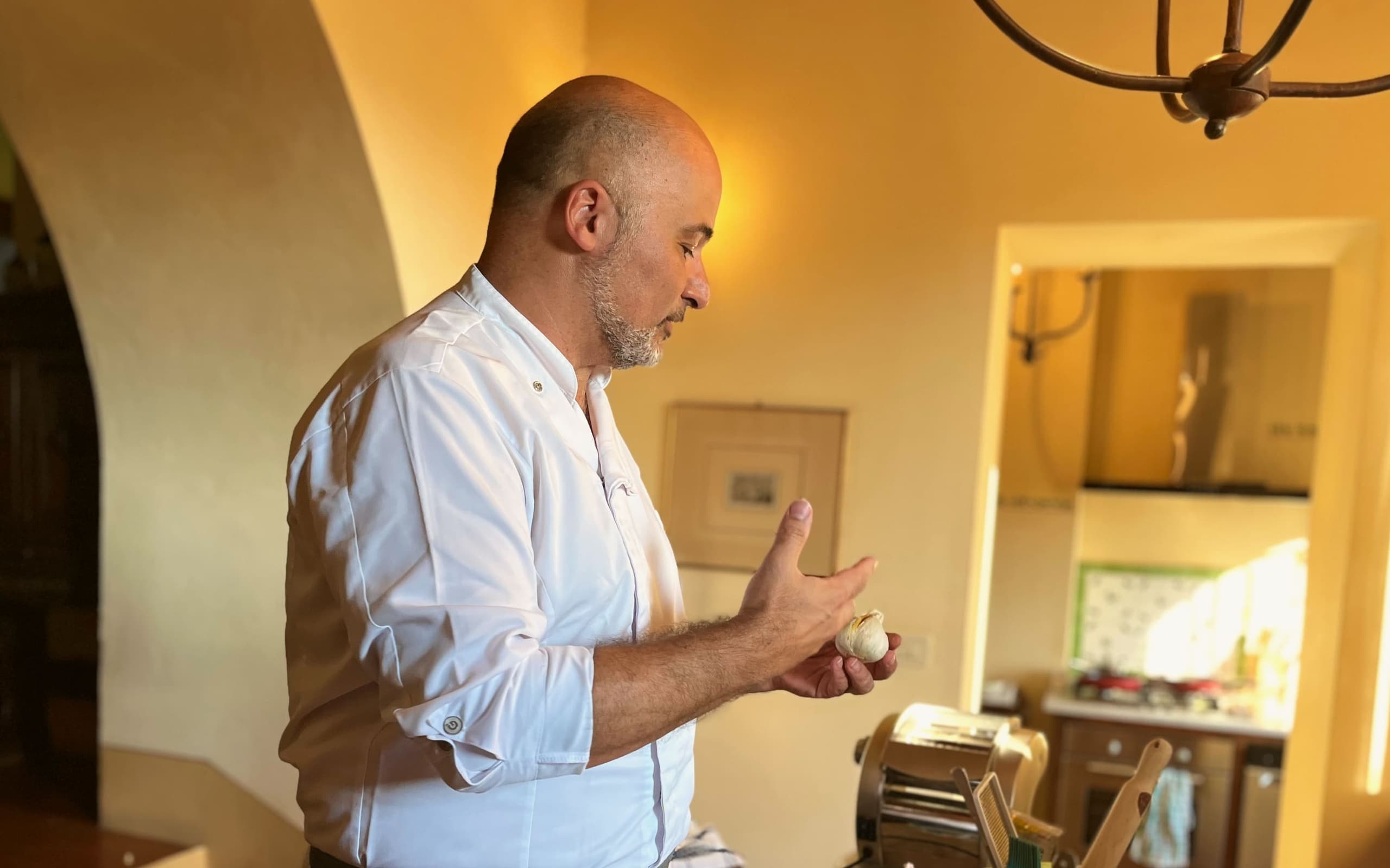 Roberto al lavoro nella cucina a volta di una villa toscana, con la macchina della pasta sul piano.